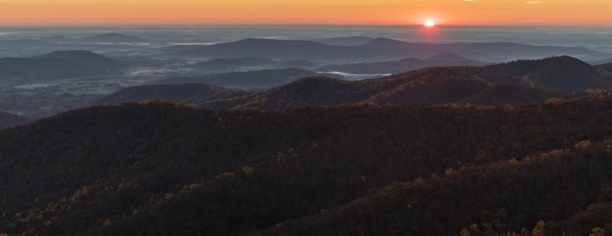 Horizon and sunrise over landscape of hills in late fall