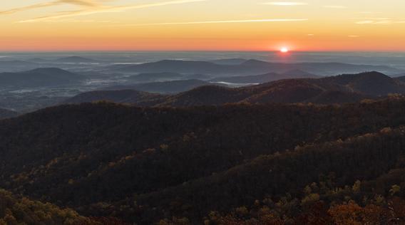 Horizon and sunrise over landscape of hills in late fall