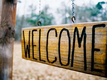Hanging wood sign with word spelling welcome