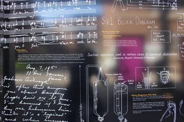 Black wall with various writing examples including music, diagrams, charts